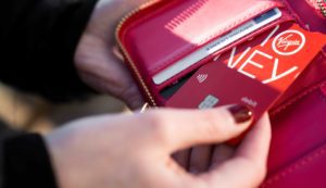 Hand holding a pink purse pulling out a bank card.