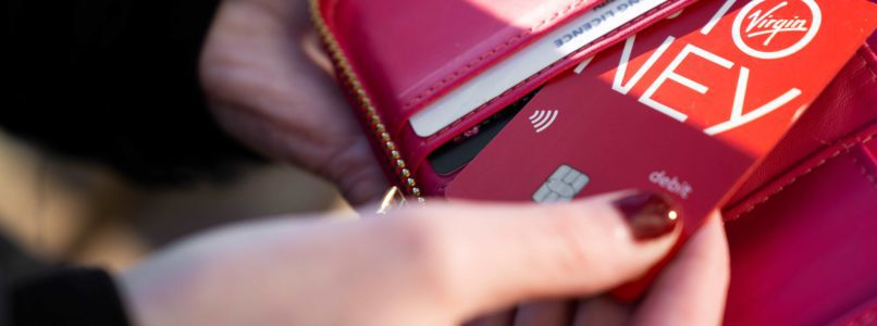 Hand holding a pink purse pulling out a bank card.