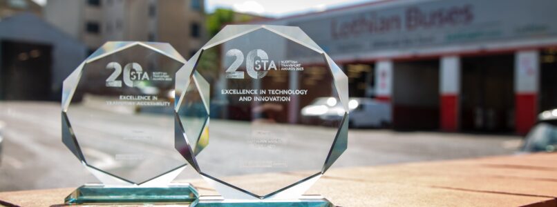 The two glass awards sitting on a wall in the sunshine in front of the bus garage.