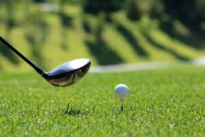 A golf club about to hit a ball on a tee.
