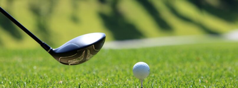 A golf club about to hit a ball on a tee.