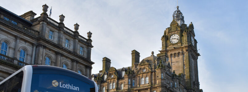 Image shows the top of a city bus with the Balmoral Hotel and clock in the background, set against a sunny blue sky.
