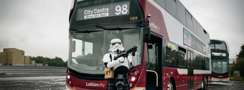 A stormtrooper stands in front of a Service 98 bus.